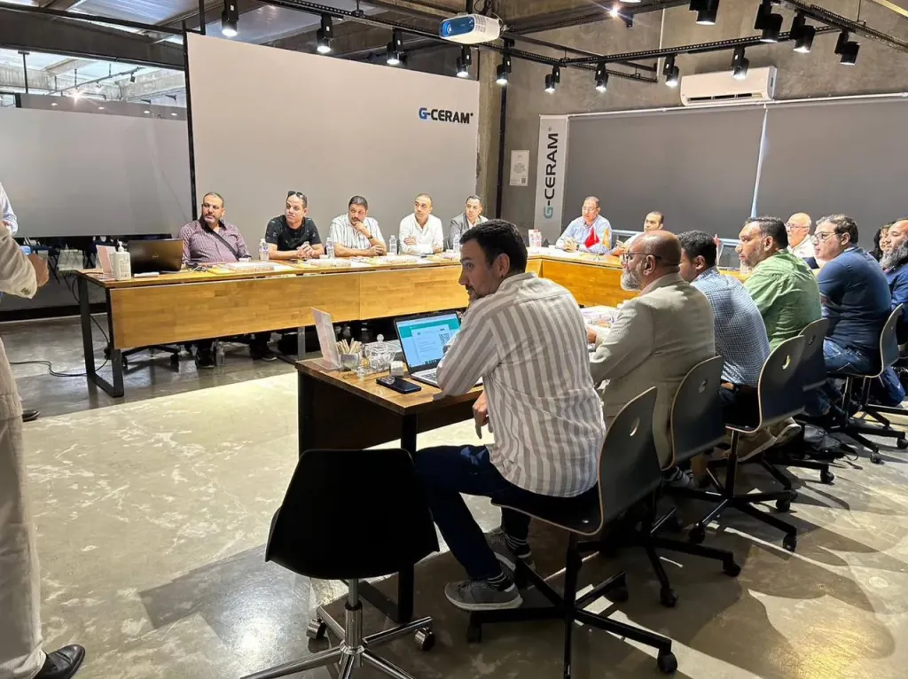 Guests seated around meeting tables in a room with G-Ceram banners